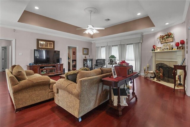 135 Maud Olive Dr, Belle Chasse, LA 70037 - living room with a tray ceiling, ceiling fan, dark wood-style flooring, crown molding, and a tiled fireplace
