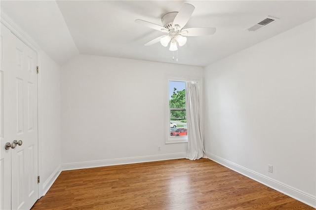 spare room featuring wood finished floors, baseboards, ceiling fan, and lofted ceiling