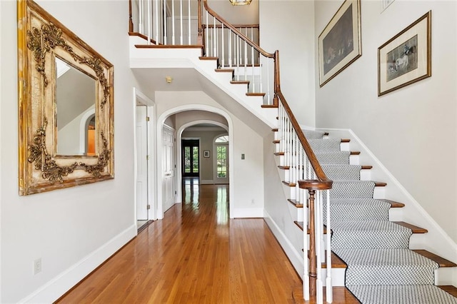 9816 Elm Pl, River Ridge, LA 70123 - foyer with arched walkways, wood finished floors, stairway, a towering ceiling, and baseboards