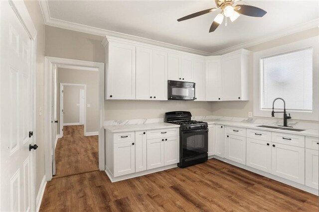 2718 Palmyra St, New Orleans, LA 70119 - kitchen with black appliances, a sink, ornamental molding, dark wood finished floors, and white cabinetry