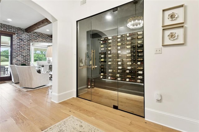 28 Wax Myrtle Ln, Covington, LA 70433 - wine cellar featuring wood finished floors, baseboards, beamed ceiling, a chandelier, and arched walkways