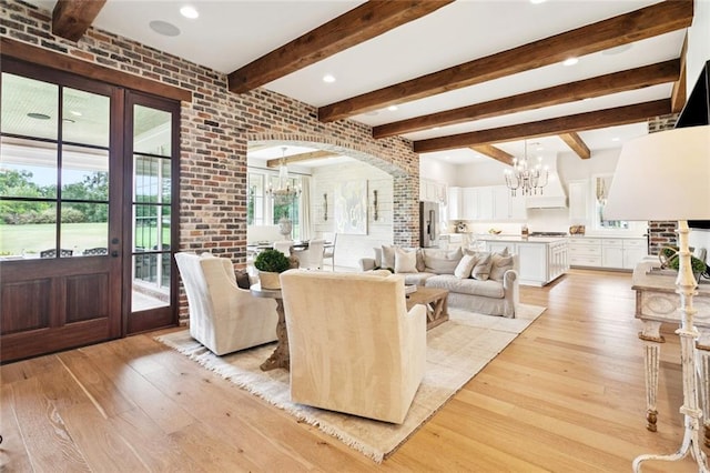28 Wax Myrtle Ln, Covington, LA 70433 - living room with a chandelier, light wood-type flooring, beam ceiling, brick wall, and arched walkways
