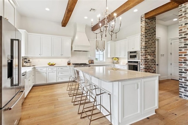 28 Wax Myrtle Ln, Covington, LA 70433 - kitchen with appliances with stainless steel finishes, custom exhaust hood, beam ceiling, light wood-style flooring, and a spacious island
