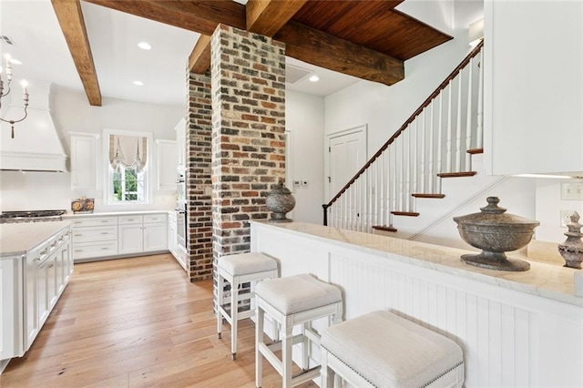 28 Wax Myrtle Ln, Covington, LA 70433 - kitchen with beam ceiling, premium range hood, light wood finished floors, white cabinetry, and light countertops