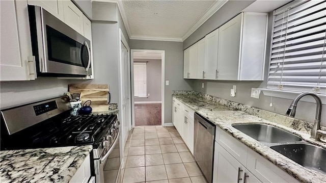1813 Green Oak Dr, Gretna, LA 70056 - kitchen with stainless steel appliances, white cabinetry, a textured ceiling, ornamental molding, and light tile patterned floors