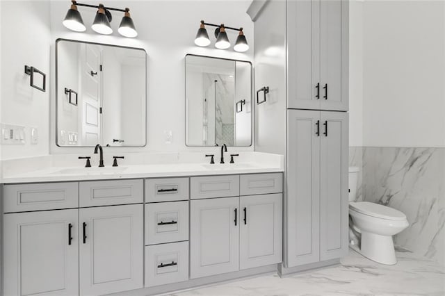 5516 Warrington Dr, New Orleans, LA 70122 - full bath with marble look tile flooring, toilet, a marble finish shower, double vanity, and a wainscoted wall