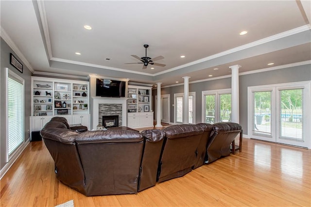 42251 Jefferson Dr, Hammond, LA 70403 - living area with a tray ceiling, light wood finished floors, decorative columns, a stone fireplace, and a ceiling fan