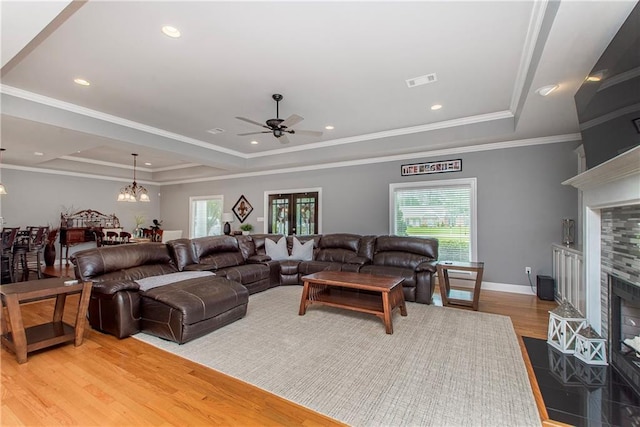 42251 Jefferson Dr, Hammond, LA 70403 - living room with a raised ceiling, a tiled fireplace, light wood-style floors, ceiling fan, and ornamental molding