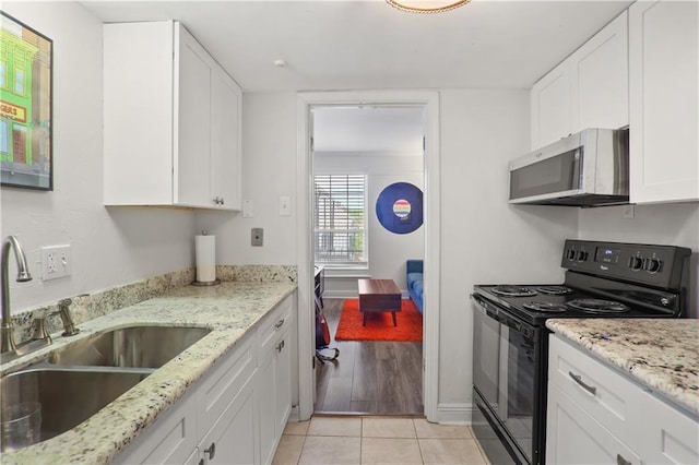 732 Cherokee St Unit 305, New Orleans, LA 70118 - kitchen featuring black electric range oven, white cabinets, light tile patterned floors, and light stone countertops