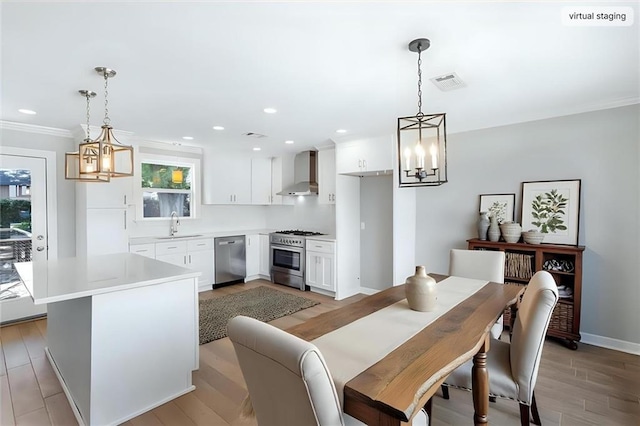 2308 Taft Park, Metairie, LA 70001 - kitchen with stainless steel appliances, wall chimney exhaust hood, a chandelier, white cabinets, and light countertops