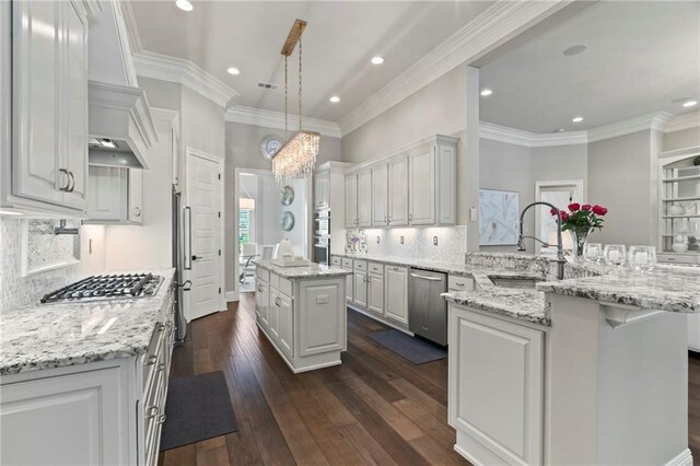 331 Memphis Trce, Covington, LA 70433 - kitchen featuring appliances with stainless steel finishes, a peninsula, a center island, white cabinets, and decorative backsplash