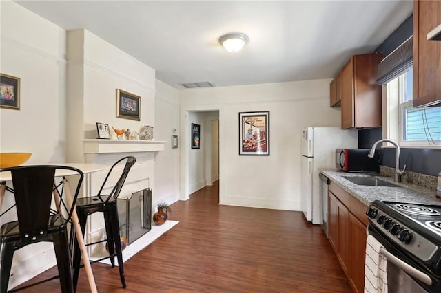 4709-11 Coliseum St, New Orleans, LA 70115 - kitchen featuring a sink, dark wood-style floors, brown cabinetry, appliances with stainless steel finishes, and a fireplace