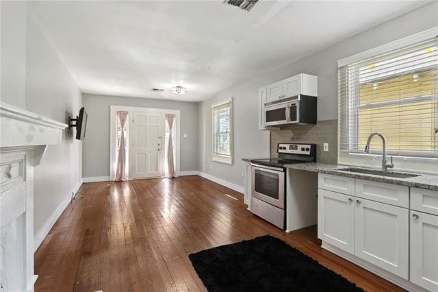 4709-11 Coliseum St, New Orleans, LA 70115 - kitchen with stainless steel appliances, a sink, dark wood-style floors, baseboards, and white cabinetry