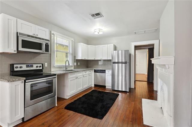 4709-11 Coliseum St, New Orleans, LA 70115 - kitchen featuring appliances with stainless steel finishes, a sink, white cabinetry, tasteful backsplash, and dark wood-type flooring