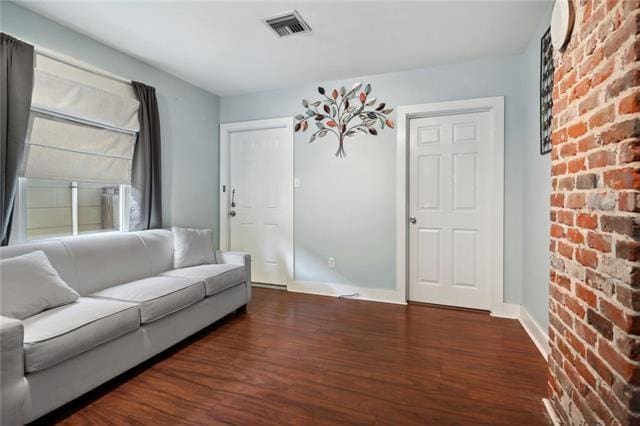 4709-11 Coliseum St, New Orleans, LA 70115 - living area with wood finished floors, brick wall, and baseboards