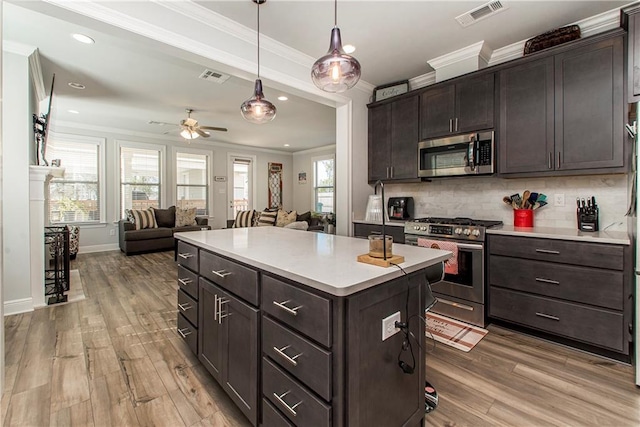 2329 Bradbury Pl, Covington, LA 70433 - kitchen featuring stainless steel appliances, ornamental molding, open floor plan, dark brown cabinetry, and light wood finished floors
