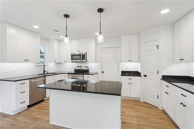 625 Woodridge Blvd, Mandeville, LA 70471 - kitchen featuring stainless steel appliances, a sink, light wood-style flooring, dark countertops, and recessed lighting