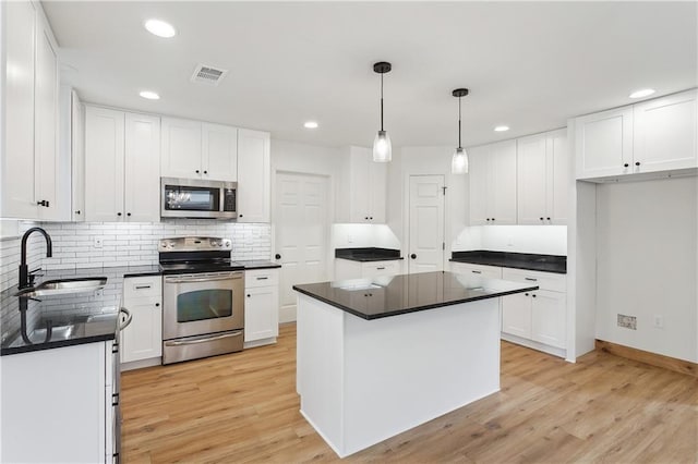 625 Woodridge Blvd, Mandeville, LA 70471 - kitchen with stainless steel appliances, a sink, dark countertops, light wood-type flooring, and tasteful backsplash