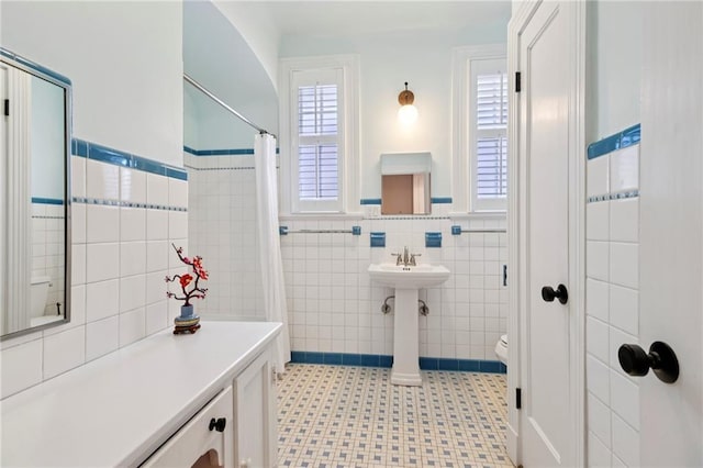 5930 Memphis St, New Orleans, LA 70124 - bathroom with tile walls, toilet, wainscoting, tile patterned floors, and a shower with curtain