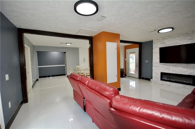 213 Travis Dr, Westwego, LA 70094 - tiled living room with a textured ceiling, a glass covered fireplace, baseboards, and attic access