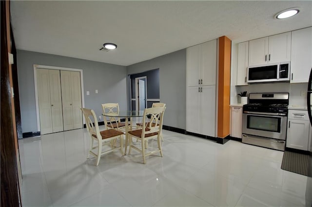 213 Travis Dr, Westwego, LA 70094 - kitchen featuring white microwave, stainless steel range with gas stovetop, white cabinets, baseboards, and recessed lighting