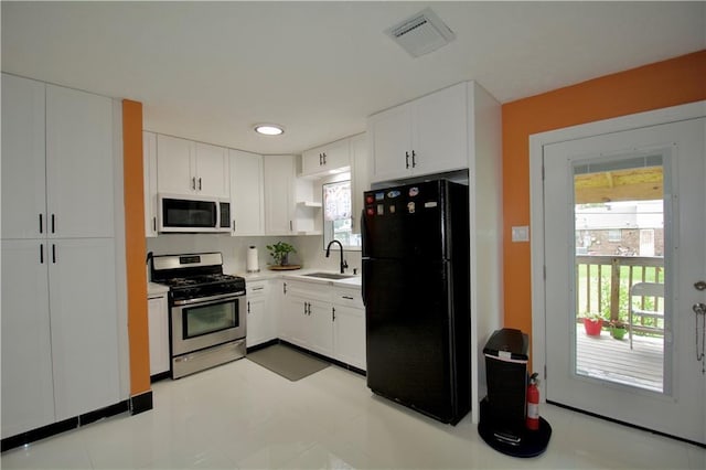 213 Travis Dr, Westwego, LA 70094 - kitchen featuring stainless steel range with gas stovetop, freestanding refrigerator, white microwave, white cabinets, and a sink