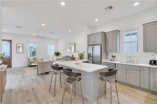 2509 Palmyra St, New Orleans, LA 70119 - kitchen featuring gray cabinetry, appliances with stainless steel finishes, a breakfast bar area, a kitchen island, and light countertops