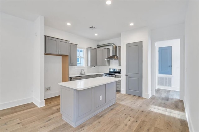 2509 Palmyra St, New Orleans, LA 70119 - kitchen featuring gray cabinetry, appliances with stainless steel finishes, wall chimney exhaust hood, light countertops, and light wood-style flooring