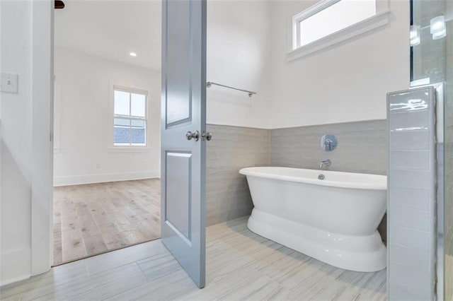 2509 Palmyra St, New Orleans, LA 70119 - bathroom with a freestanding tub, tile walls, wood finished floors, and wainscoting