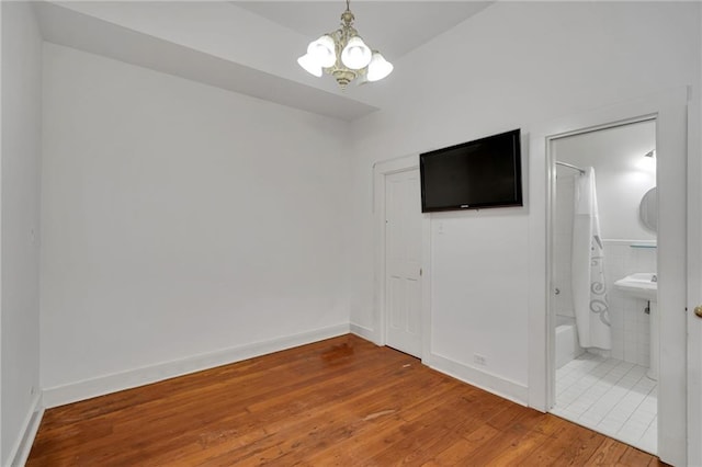 526 Madison St Unit 1B, New Orleans, LA 70116 - unfurnished bedroom with a chandelier, hardwood / wood-style floors, and ensuite bathroom