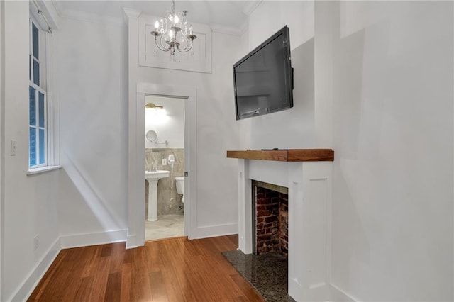 526 Madison St Unit 1B, New Orleans, LA 70116 - unfurnished living room with wood finished floors, a chandelier, crown molding, and a fireplace with flush hearth