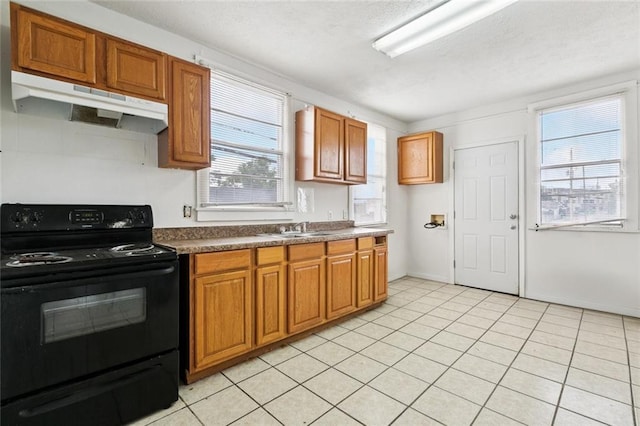 3500 Clematis St, New Orleans, LA 70123 - kitchen with electric range, under cabinet range hood, brown cabinets, dark countertops, and light tile patterned floors