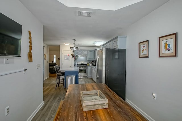 70380 K St, Covington, LA 70433 - kitchen with stainless steel appliances, a breakfast bar area, dark wood-style floors, and gray cabinets