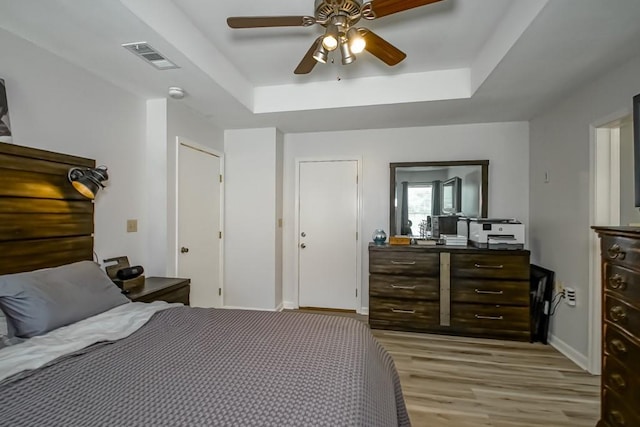 70380 K St, Covington, LA 70433 - bedroom featuring light wood-type flooring, a tray ceiling, and ceiling fan