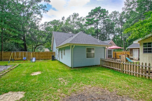 70380 K St, Covington, LA 70433 - rear view of house with a shingled roof, a playground, and a fenced backyard