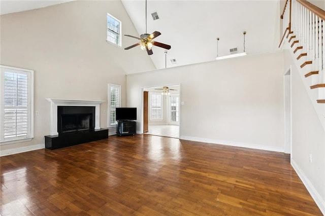 175 Dunleith Dr, Destrehan, LA 70047 - unfurnished living room with ceiling fan, high vaulted ceiling, stairs, wood finished floors, and a fireplace with raised hearth
