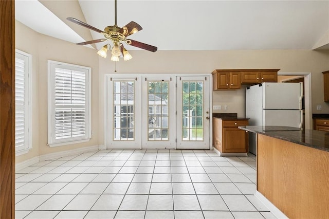 175 Dunleith Dr, Destrehan, LA 70047 - kitchen with vaulted ceiling, brown cabinets, ceiling fan, light tile patterned floors, and freestanding refrigerator