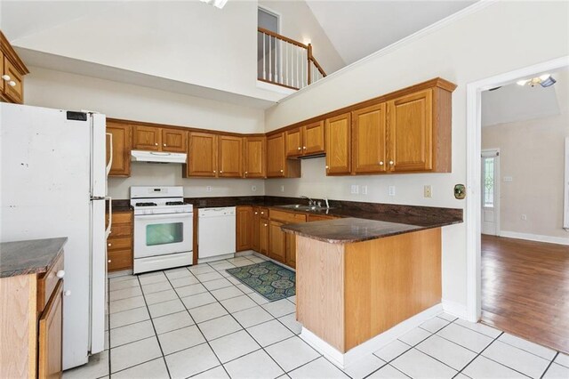 175 Dunleith Dr, Destrehan, LA 70047 - kitchen with white appliances, under cabinet range hood, a peninsula, dark countertops, and high vaulted ceiling