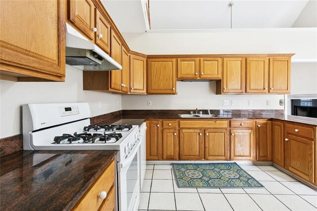 175 Dunleith Dr, Destrehan, LA 70047 - kitchen with white range with gas cooktop, under cabinet range hood, black microwave, and brown cabinets