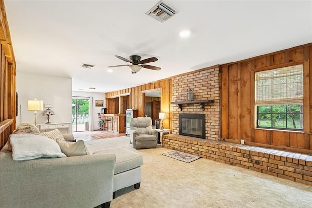20226 Chandler Dr, Covington, LA 70435 - living room featuring wood walls, a fireplace, carpet floors, and a ceiling fan