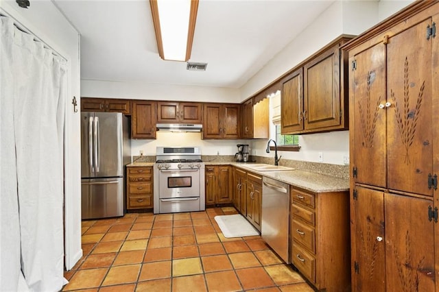 20226 Chandler Dr, Covington, LA 70435 - kitchen featuring stainless steel appliances, under cabinet range hood, light countertops, brown cabinets, and light tile patterned floors