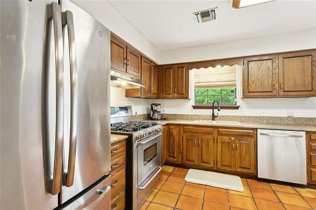 20226 Chandler Dr, Covington, LA 70435 - kitchen with stainless steel appliances, under cabinet range hood, and brown cabinetry