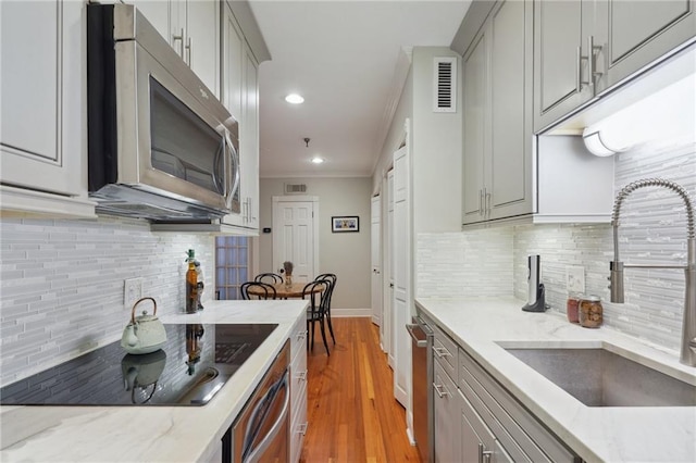 214 Chartres St Unit 3, New Orleans, LA 70130 - kitchen with stainless steel appliances, gray cabinets, decorative backsplash, recessed lighting, and light stone countertops