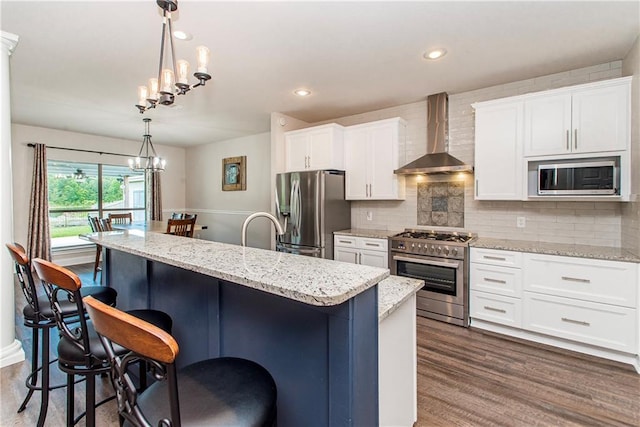 42013 Red Maple St, Hammond, LA 70403 - kitchen with stainless steel appliances, wall chimney range hood, a kitchen breakfast bar, a chandelier, and dark wood-style flooring
