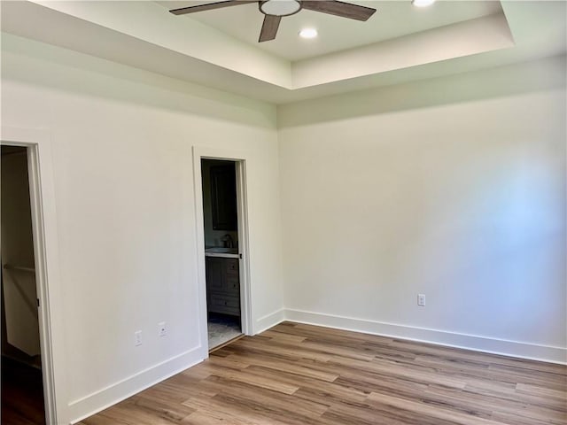 2019 Huey P Long Ave, Gretna, LA 70053 - unfurnished bedroom with wood finished floors, connected bathroom, a tray ceiling, recessed lighting, and a ceiling fan