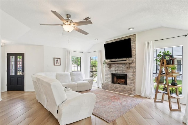 104 Inverrary Ct, Slidell, LA 70460 - living room featuring lofted ceiling, light wood finished floors, a fireplace, a ceiling fan, and a textured ceiling
