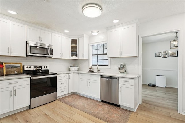 104 Inverrary Ct, Slidell, LA 70460 - kitchen featuring appliances with stainless steel finishes, light countertops, backsplash, white cabinets, and light wood-type flooring