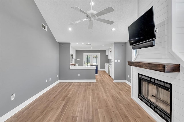 506 Ellington Ave, Luling, LA 70070 - unfurnished living room featuring a large fireplace, light wood finished floors, a ceiling fan, a textured ceiling, and lofted ceiling