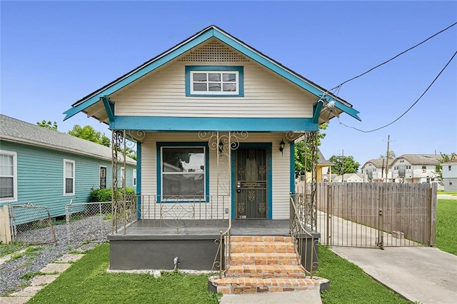 8711 Olive St, New Orleans, LA 70118 - shotgun-style home featuring covered porch and a gate