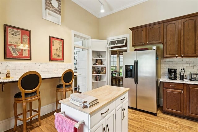 39267 Z Oaks Ln, Ponchatoula, LA 70454 - kitchen featuring stainless steel fridge with ice dispenser, ornamental molding, light wood-type flooring, a breakfast bar area, and white cabinets